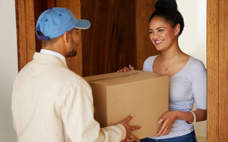 Shot of a delivery man making a delivery to a customer at her home
